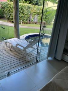 a glass porch with a chair and a swimming pool at Apartamento Villas do Pratagy in Maceió