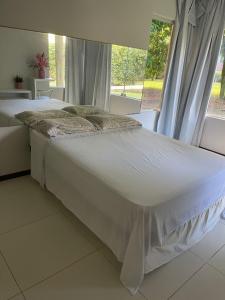 Cama blanca en habitación con ventana en Apartamento Villas do Pratagy, en Maceió