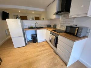 eine Küche mit weißen Schränken, einer Mikrowelle und einer Spüle in der Unterkunft LT Apartments 54 - Twin Bed Apartment in Leicester