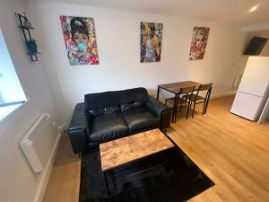 ein Wohnzimmer mit einem schwarzen Ledersofa und einem Tisch in der Unterkunft LT Apartments 54 - Twin Bed Apartment in Leicester