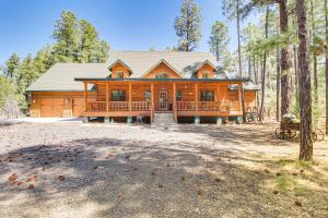 a large log cabin in the woods with a porch at Rustic Lakeside Cabin on 3 Acres w/ Nature Views! in Pinetop-Lakeside