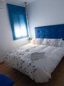 une chambre avec un grand lit et une tête de lit bleue dans l'établissement Apartamento Caravaca, à Santa Pola