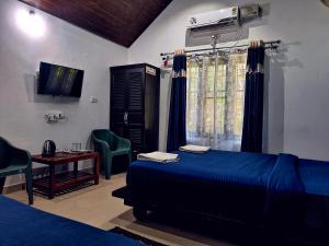 1 dormitorio con 1 cama azul, mesa y sillas en The Twin Cottages, en Madikeri