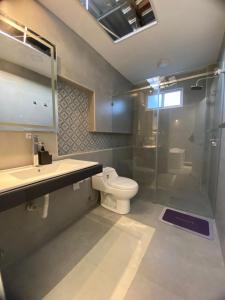 een badkamer met een douche, een toilet en een wastafel bij Hermosa suite 3 elegante con jacuzzi in Guayaquil