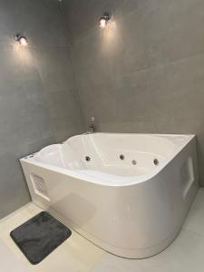 a white bath tub in a bathroom with two lights at Hermosa suite 3 elegante con jacuzzi in Guayaquil