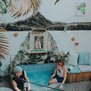 Un hombre y una mujer sentados en una piscina en Casa Coco Hostel, en Santa Ana
