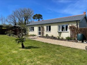 a house with a small palm tree in a yard at Grandma's Honeycomb Cottage - a quiet, charming, cosy retreat in the countryside only 2 miles from one of Cornwall's best beaches in Truro