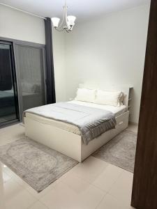 a white bedroom with a bed with white sheets and pillows at 1 BHK in Al Khan Sharjah in Sharjah