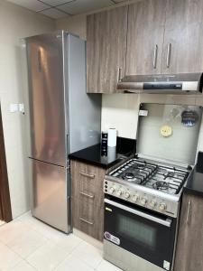 a kitchen with a stove and a stainless steel refrigerator at 1 BHK in Al Khan Sharjah in Sharjah