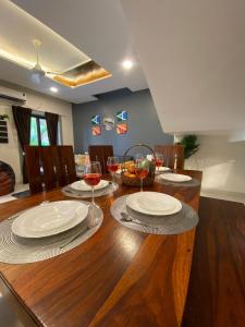 a wooden table with plates and wine glasses on it at 3BHK Villa Vikings Stay near candolim in Nerul