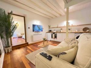 a living room with a white couch and a kitchen at LES SEYCHELLES, T2, Hyper Centre, Cours intérieure in Mâcon