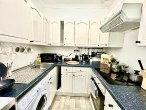 a kitchen with white cabinets and a sink at Cosy stylish Dumbarton flat in Dumbarton
