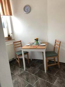 a table with two chairs and a clock on the wall at Ferienwohnung Alex in Kirchenlamitz