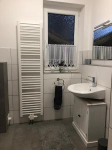 a white bathroom with a sink and a window at Ferienwohnung Alex in Kirchenlamitz