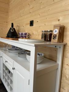a kitchen with a white counter with dishes on it at Gościn nad Drawą Glamping in Drawno