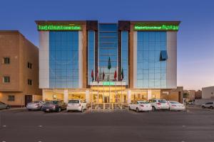 un gran edificio con coches estacionados en un estacionamiento en Burj Alhayah Hotel Suites Alfalah en Riad