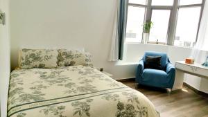 1 dormitorio con 1 cama y 1 silla azul en Ms. Zhang's Flat 303, en Abu Dabi