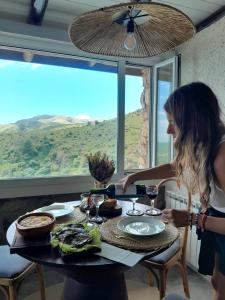 a woman sitting at a table with a plate of food at Establecimiento La Soleada suites de campo in La Cumbre