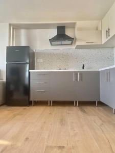 a kitchen with a black refrigerator and a wooden floor at Ocean Sun 4 in Fira