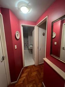a bathroom with a red wall and a mirror at Departamento temporal 2 ambientes in Buenos Aires