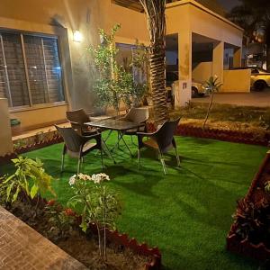 une terrasse avec une table et des chaises sur de l'herbe verte dans l'établissement Holidazzle Villa, à Karachi
