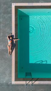Eine Frau im Bikini sitzt neben einem Pool. in der Unterkunft Monte Prado Hotel & Spa in Melgaço