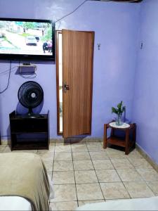 a bedroom with a tv and a bed and a door at 7 camas de casal - Casa próxima ao Bumbódromo in Parintins