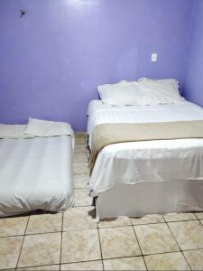 2 Betten nebeneinander in einem Zimmer in der Unterkunft 7 camas de casal - Casa próxima ao Bumbódromo in Parintins