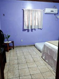 a room with two beds and a window and a tiled floor at 7 camas de casal - Casa próxima ao Bumbódromo in Parintins