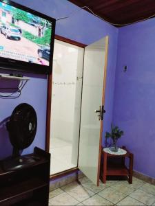 Zimmer mit einem TV und einer Glasschiebetür in der Unterkunft 7 camas de casal - Casa próxima ao Bumbódromo in Parintins