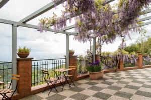 eine Terrasse mit lila Glyzinien, die von einer Pergola hängt in der Unterkunft Bed&Breakfast Bella Vita in Bracco