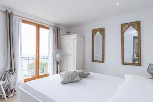 ein weißes Schlafzimmer mit einem großen Bett mit zwei Spiegeln in der Unterkunft Villa de luxe à Eze in Èze