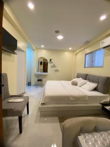 um quarto com uma grande cama branca e uma cadeira em Microsuite 2 en Guayaquil elegante y privada em Guayaquil