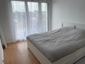 - un lit blanc dans une chambre avec fenêtres dans l'établissement Appartement spacieux et cosy 20 min to Paris & JO 2024, à Sannois