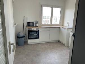 uma cozinha com armários brancos, um micro-ondas e uma janela em Appartement spacieux et cosy 20 min to Paris & JO 2024 em Sannois