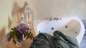 ein Badezimmer mit einer weißen Badewanne und einer Vase aus lila Blumen in der Unterkunft La Pecora Nera in Rocchetta Nervina