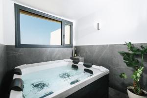 uma grande banheira na casa de banho com uma janela em Alcyone Studios and Apartments em Iráclio