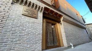 un edificio de ladrillo con una puerta y una señal en él en Mahbubakhon Hotel, en Bukhara