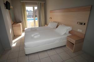 Un dormitorio con una gran cama blanca y una ventana en Alexandros Studios Moraitika en Moraitika