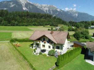 a house in a field with mountains in the background at Terezia-Appartements Nassfeld in Hermagor