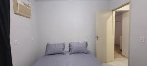 uma cama num quarto branco com duas almofadas em Casa ao lado da Dubai brasileira em Camboriú