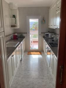 una cocina con armarios blancos y una puerta que conduce a un patio en Casa La Vida, stijlvolle Spaanse villa met uniek uitzicht!, en Benitachell