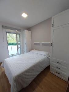 Un dormitorio con una gran cama blanca y una ventana en Apartamento en Unquera, en Unquera