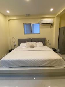 1 dormitorio con 1 cama grande con sábanas blancas y ventana en Microsuite 1 hermosa y privada, en Guayaquil