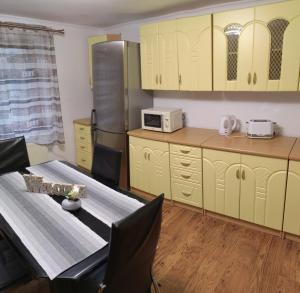 シビウにあるVila dintre braziのキッチン(黄色のキャビネット、テーブル、冷蔵庫付)