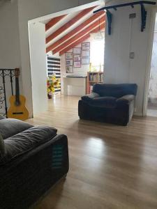 una sala de estar con 2 sofás y una guitarra en Dulces Sueños, en Chillán