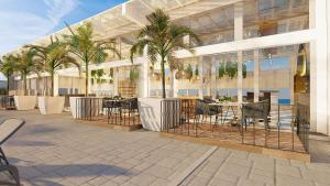a large white building with palm trees and a patio at Bellafer Collection Hotel & Resort in Rosarito