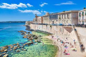 een groep mensen op een strand naast de oceaan bij Casa Felice in Siracusa