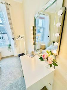 een badkamer met een spiegel en een vaas met bloemen op een aanrecht bij Dumbarton cosy home, Loch Lomond in Dumbarton