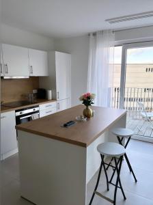 une cuisine avec des placards blancs et un comptoir avec des tabourets dans l'établissement Joli appartement haut standing Liège Centre, à Liège